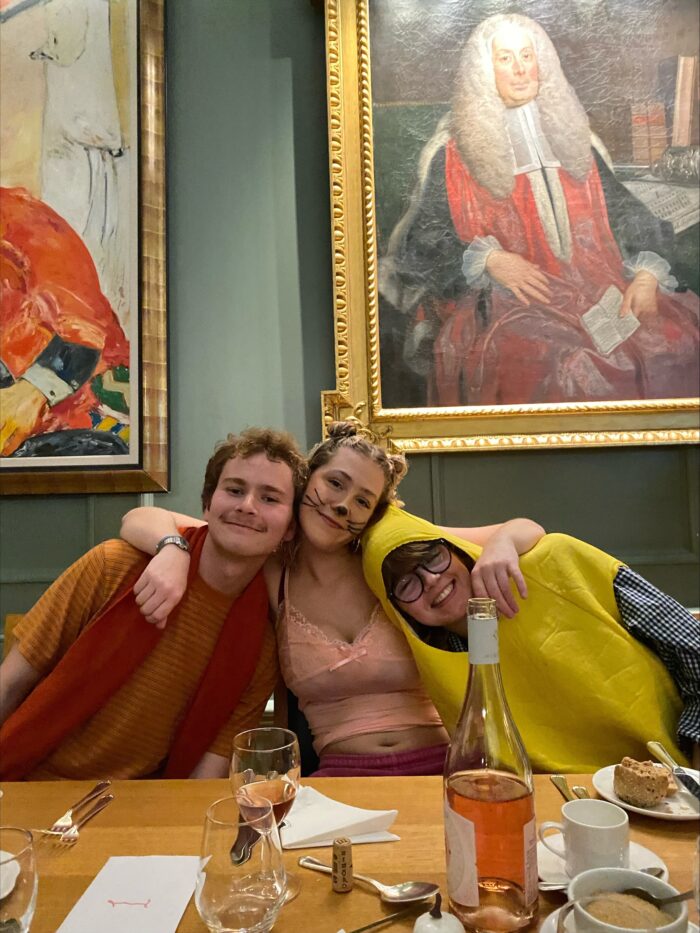 Three students dining at a formal in fancy dress.